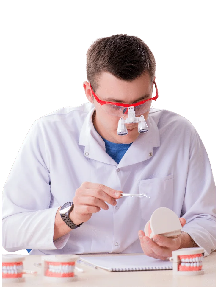 Periodontist wearing a white coat and goggles holding a model of a jaw